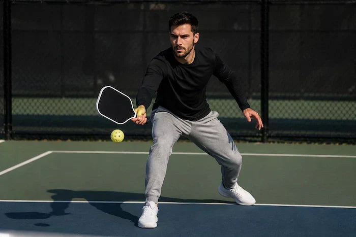 Joueur de pickleball en position basse prêt à frapper la balle sur un terrain