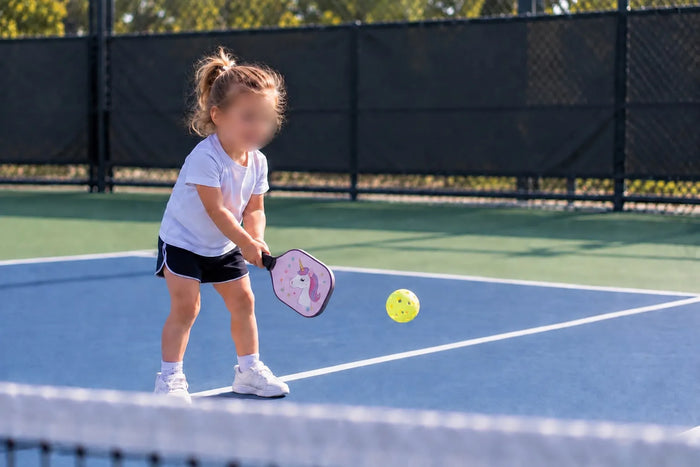 Jeune enfant découvrant le pickleball avec une raquette adaptée sur un terrain