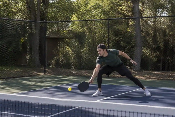Joueur de pickleball défendant un smash avec une balle basse près du filet