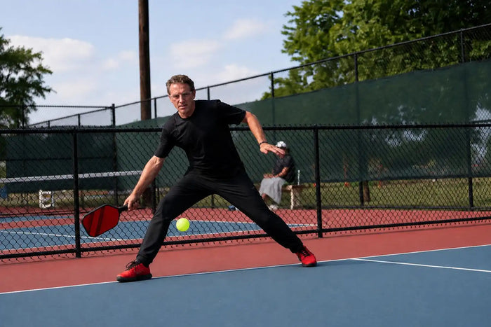 Homme réalisant un slice au pickleball sur un terrain extérieur.