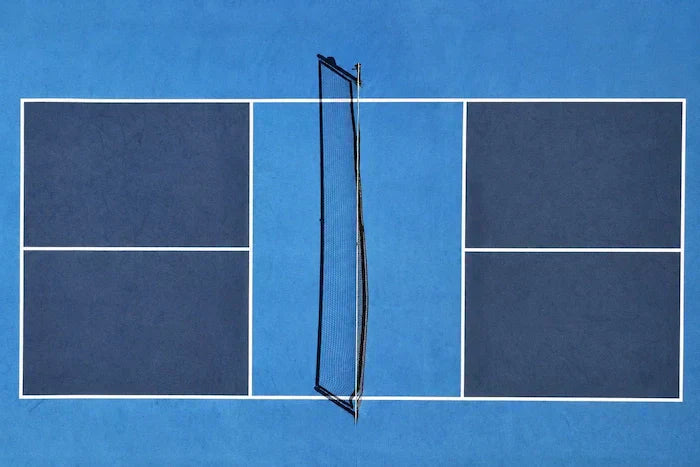 Terrain de pickleball vu du dessus avec filet au centre et lignes blanches sur surface bleue