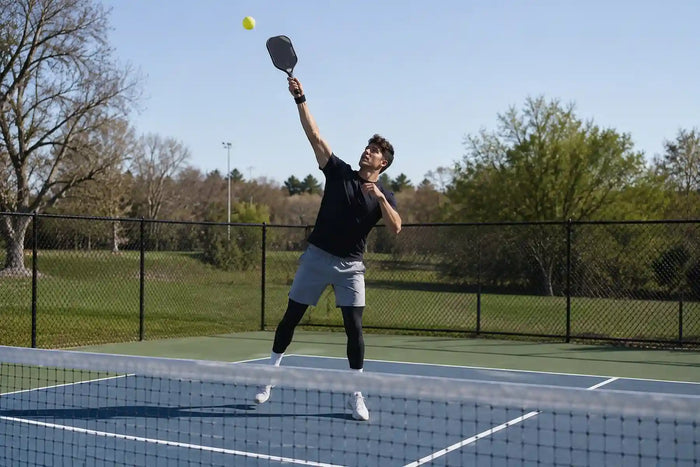 Joueur de pickleball se préparant à défendre un lob avec une frappe au-dessus de la tête.
