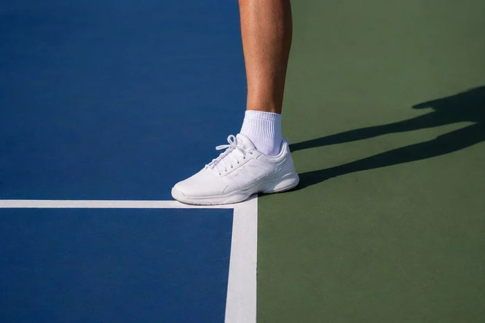 Pied d'un joueur de pickleball qui mord la ligne de fond pendant un service, illustrant une faute de pied.
