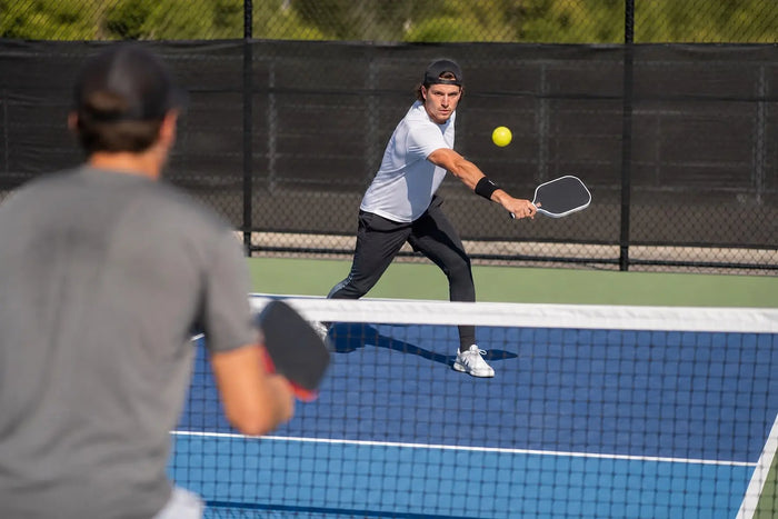 Joueur gaucher frappant la balle lors d’un échange de pickleball.