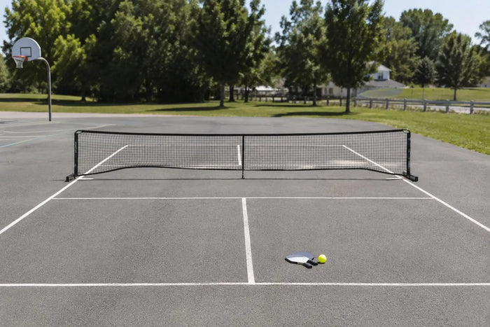 Terrain polyvalent avec un filet portable de pickleball installé, illustrant qu’il est possible de jouer au pickleball sans terrain dédié.