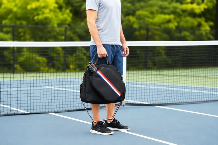 Joueur tenant un sac de pickleball sur un terrain extérieur, illustrant les différents critères pour choisir un sac adapté à sa pratique.