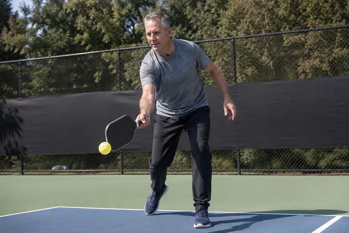 Senior jouant au pickleball en plein air sur un terrain extérieur 