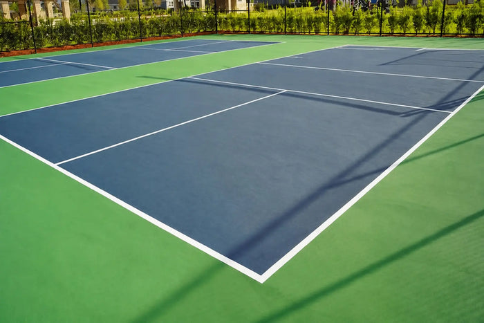 Terrain de pickleball extérieur sans filet, avec les lignes réglementaires visibles et un revêtement bleu et vert.