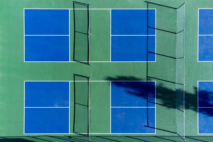 Vue aérienne de plusieurs terrains de pickleball extérieurs avec lignes de jeu bleues, surface verte et filets au centre des courts
