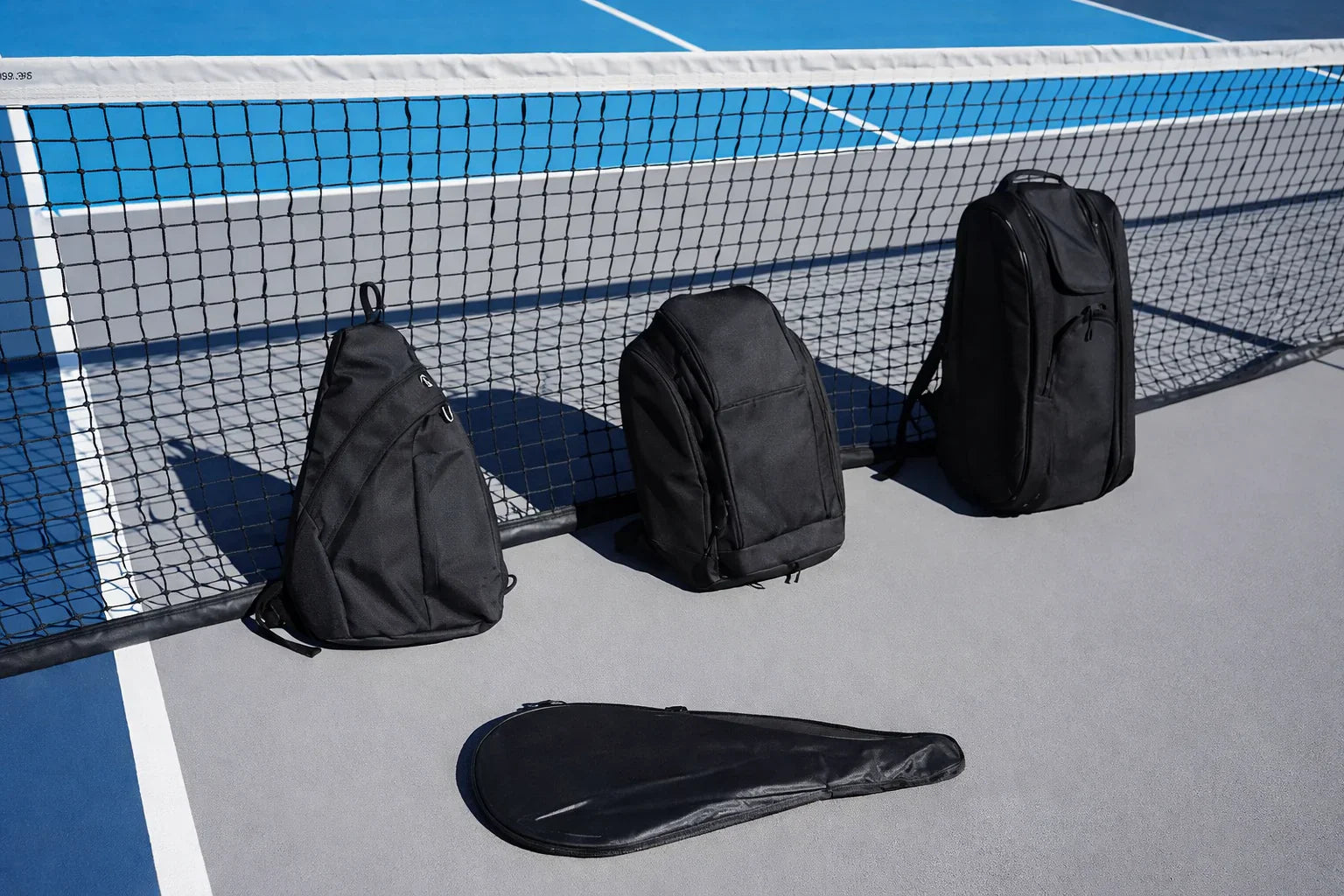 Assortiments de sacs pour raquettes de pickleball posés sur un terrain.