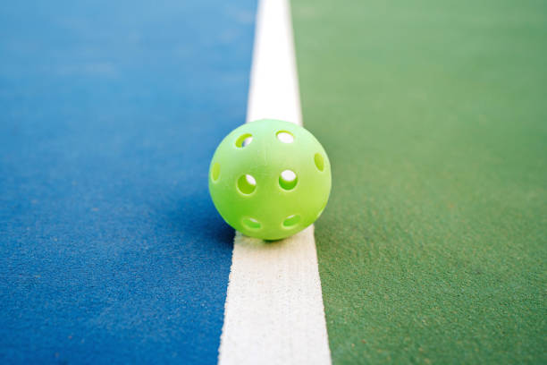 Balles de pickleball indoor et outdoor posées sur un terrain