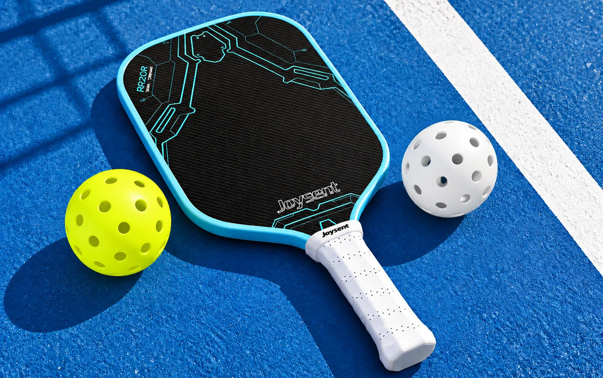 Raquette Joysent Razor et deux balles outdoor jaune fluo et blanche sur un terrain bleu