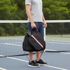 Joueur sur un court de pickleball portant à la main le sac de sport noir à sangles tricolores, montrant la housse extérieure contenant deux raquettes.